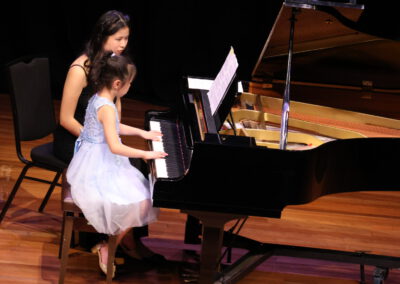 A girl playing piano with her teacher.