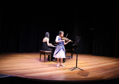 Kids on a stage playing instruments.